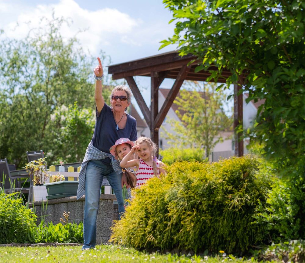 Seniorin zeigt zwei Mädchen etwas am Himmel