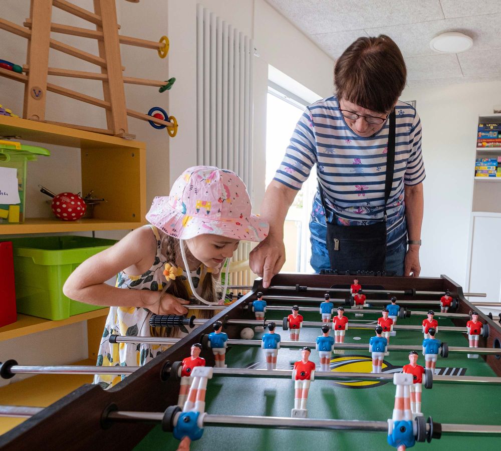 Kind und Seniorin spielen Tischkicker